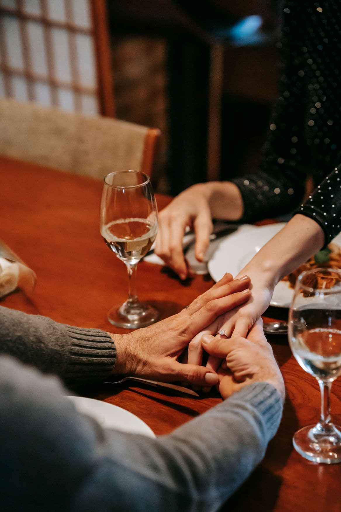 Two people holding hands across a dinner table.