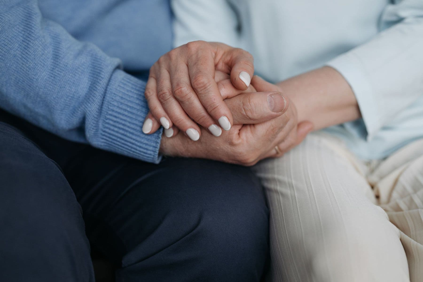 Two people holding hands, seen close up.