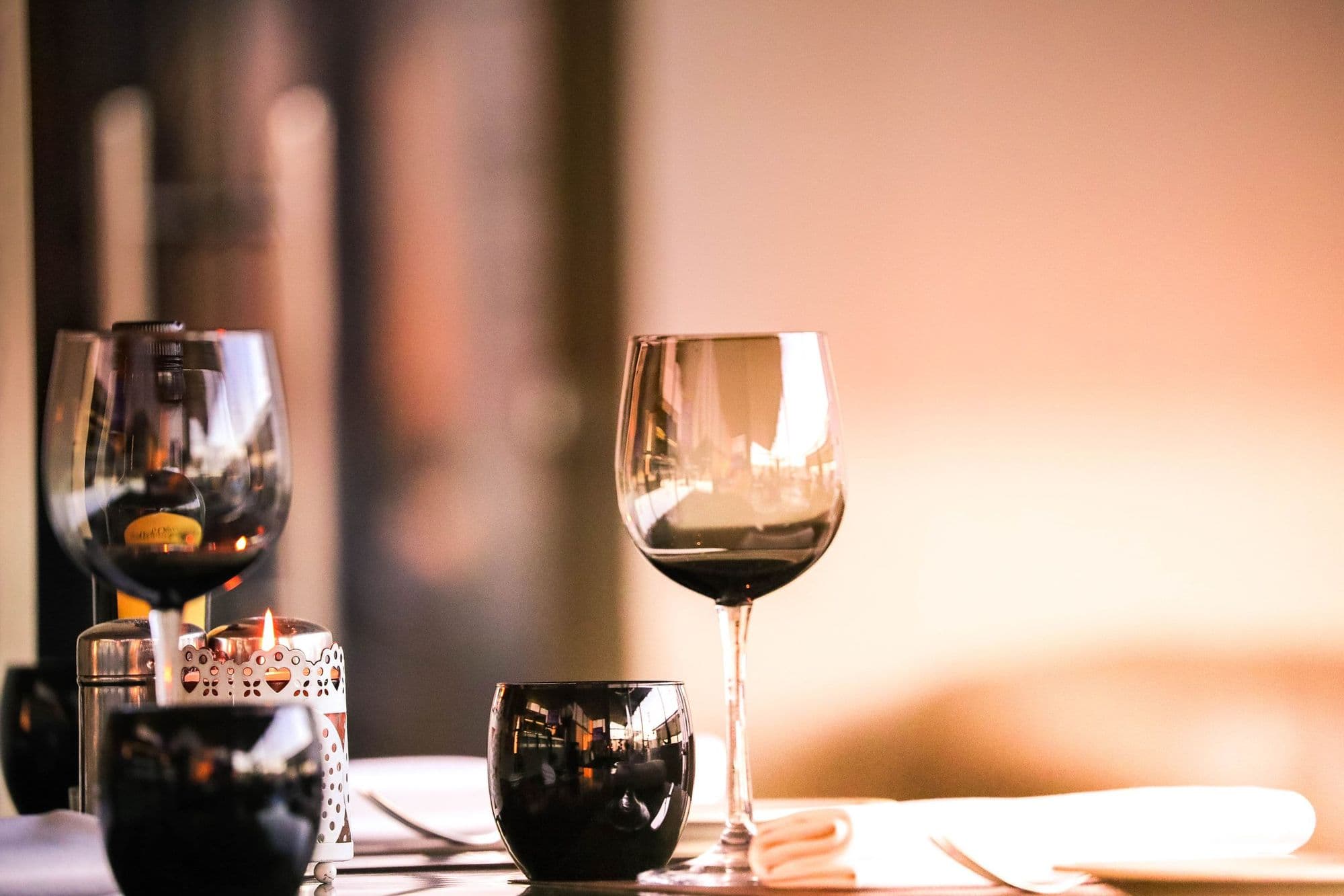 Two wine glasses on a candlelit table.